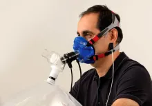 Person wearing a CPET mask connected to respiratory testing equipment during a cardiopulmonary exercise assessment.